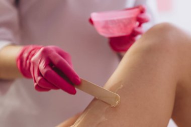 Spa lüks stüdyosunda saç kesimi. Kadın bacakları titreyerek ağda yapıyor. Sıcak şeker.