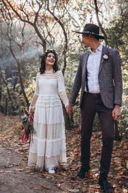 Gün batımında parkta düğün fotoğrafı çektiren zarif bir çift gelin.