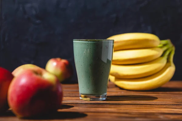 The concept of food and drink, diet and nutrition. Healthy green vegan smoothie with banana, spirulina and ripe apple for summer detoxification