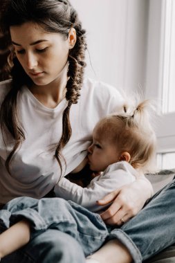 Anne göğsünden süt emen bir çocuğun portresi. Dişi, küçük kızını kollarında emziriyor. seçici odak, gürültü etkisi