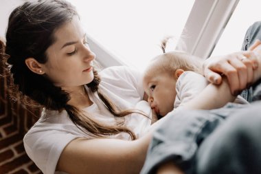 Anne göğsünden süt emen bir çocuğun portresi. Dişi, küçük kızını kollarında emziriyor. seçici odak, gürültü etkisi