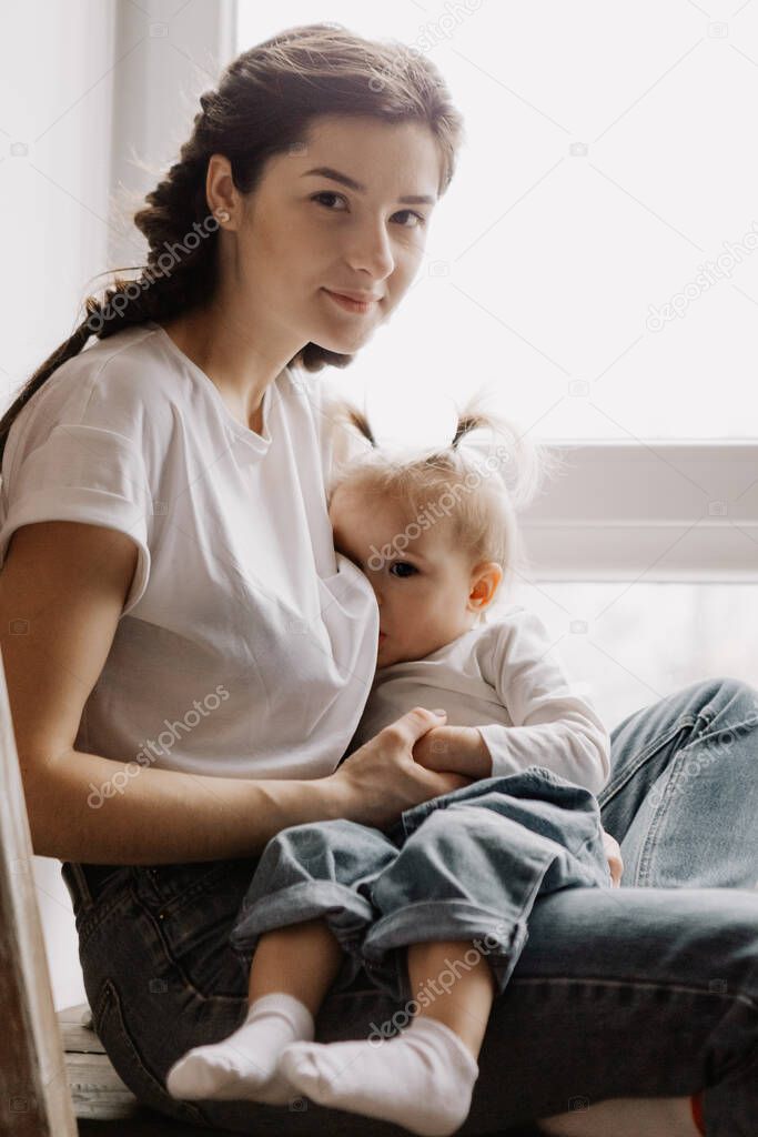 portrait of a child who sucks the milk from mother breast. Female breastfeeding her little daughter in her arms.  selective focus, noise effect