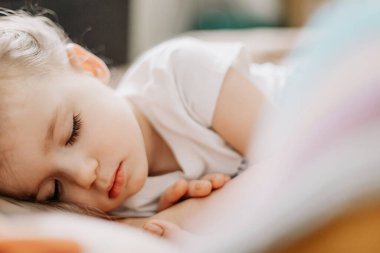 İki yıllık genç anne ve bebek birlikte uyur, sarılır, gündüz uykusunda çocuklar için konsept olur. Annem bebeğini uyuturken uyuyakalmış.