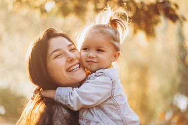 Parkta annesini kucaklayan kız, sonbahar parkında bir hafta sonu yürüyüşü yapıyor. seçici odak, gürültü etkisi,
