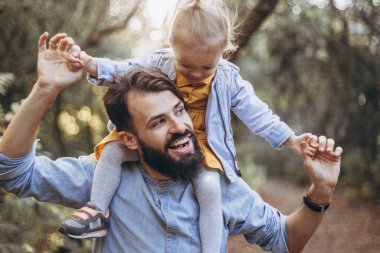 Mutlu baba-kız güzel bir sonbahar parkında yürürken oynuyorlar. Küçük kızıyla mükemmel bir hafta sonu babası. seçici odak, gürültü etkisi