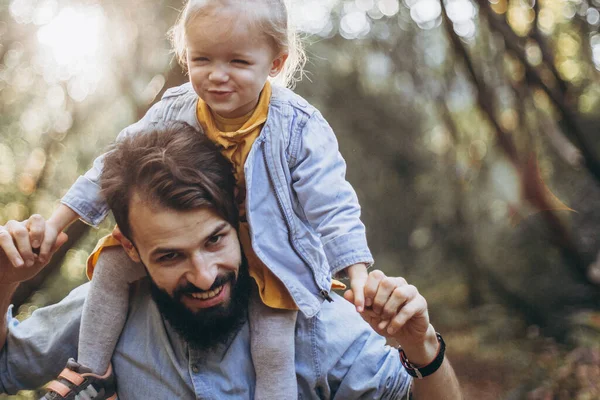Genç, şık sakallı bir baba gün batımında küçük kızıyla birlikte doğada yürüyor. Baba ve çocuğun aile fotoğrafları. seçici odak, gürültü etkisi
