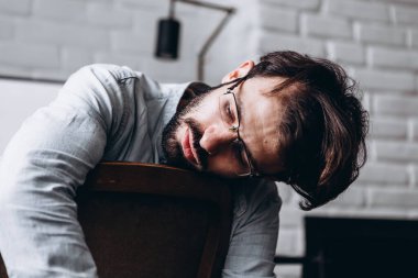 Karantina sırasında uzun bir çalışmadan sonra koltuğa yaslanmış yorgun bir adamın portresi.