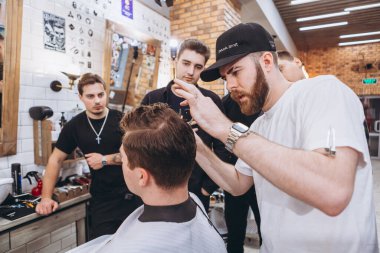 27.02.2020 Odessa, Ukrayna: Berberler profesyonel bir berberde öğrenir ve becerilerini geliştirirler. Hippi müşteri berber dükkanında haidresser ve kuaförü ziyaret ediyor.