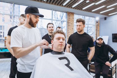 27.02.2020 Odessa, Ukrayna: Berberler profesyonel bir berberde öğrenir ve becerilerini geliştirirler. Hippi müşteri berber dükkanında haidresser ve kuaförü ziyaret ediyor.