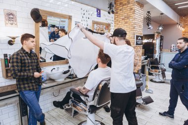 27.02.2020 Odessa, Ukrayna: Berberler profesyonel bir berberde öğrenir ve becerilerini geliştirirler. Hippi müşteri berber dükkanında haidresser ve kuaförü ziyaret ediyor.