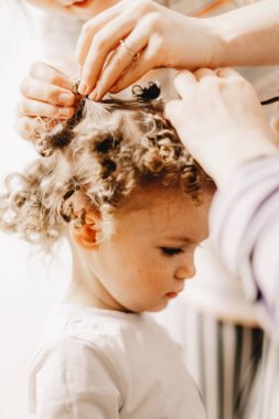 Anne ve babalar, ev yapımı bigudilerin yardımıyla kıvırcık yapmaya çalıştıkları bebeğin saçını açıyor..