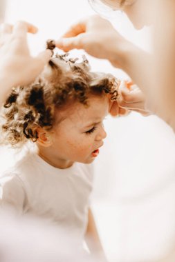 Anne ve babalar, ev yapımı bigudilerin yardımıyla kıvırcık yapmaya çalıştıkları bebeğin saçını açıyor..