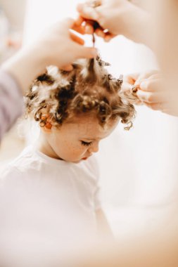 Anne ve babalar, ev yapımı bigudilerin yardımıyla kıvırcık yapmaya çalıştıkları bebeğin saçını açıyor..