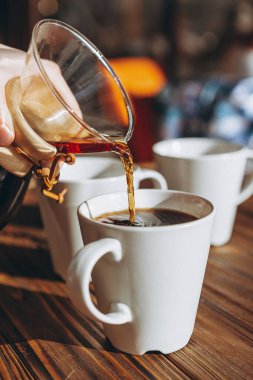 Sehpada serbest çalışan insanlar kahve içer, sohbet eder, bilgisayarda çalışır ve telefon kullanır.