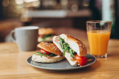 Büyük ve ağız sulandıran bir sandviç. Kahve masasının üzerinde sulu bir dolma var. Hazır kafede iki kişilik kahvaltı.