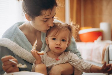 seçici odaklanma, gürültü etkisi: güzel bir kız çocuğu, annesiyle birlikte sabah mutfakta kahvaltı yapıyor.