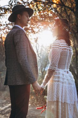 Gün batımında parkta düğün fotoğrafı çektiren zarif bir çift gelin.