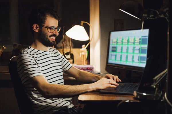 一个大胡子男人坐在电脑前的家里工作 在网上工作 — 图库照片