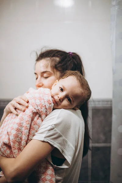 selective focus, noise effect: family is washing and bathing the baby in the bathroom, child girl have fun, she is happy and smiling, likes to enjoy water