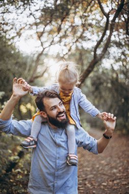 Genç, şık sakallı bir baba gün batımında küçük kızıyla birlikte doğada yürüyor. Baba ve çocuğun aile fotoğrafları. seçici odak, gürültü etkisi