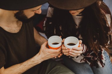 Akşam pikniğin tadını çıkaran genç ve güzel bir çift. Çay içip çayırda oturuyorlar..