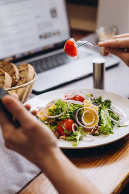 Yemek tabakları ve dizüstü bilgisayarı olan bir masa. Sıradan bir akşam yemeği, işten başka bir şey düşünmeyen bir iş adamının günlük işleriyle meşgul.