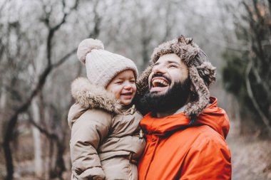 Yakışıklı genç baba ve tatlı kızı kışın dışarıda eğleniyorlar. Mutlu aile birlikte vakit geçiriyor. Aile kavramı.