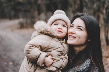 Parkta serin bir sonbahar gününde yürüyen güzel anne ve küçük kızının portresi.
