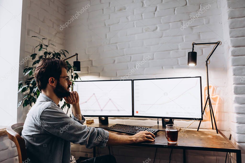 adult bearded man working sitting at home desk at computer. Self-isolation during quarantine, work at home, copy space