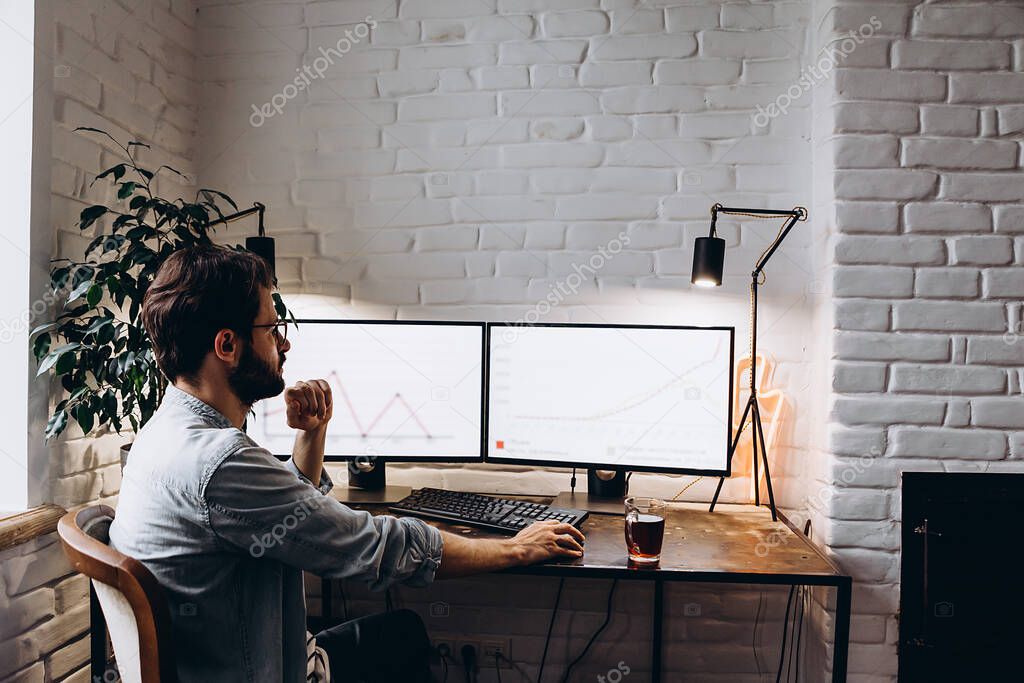 adult bearded man working sitting at home desk at computer, working online