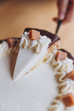 Kafe arka planında çikolata ve karamel olan iştah açıcı büyük beyaz pasta.