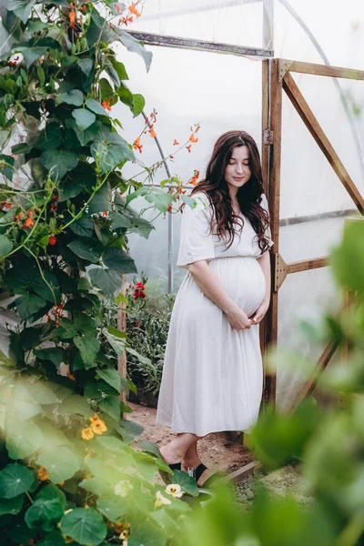 自宅のミニフラワーファームの花の間で写真のためにポーズをとって長いリネンのドレスを着たかなり若い女の子の肖像画 — ストック写真