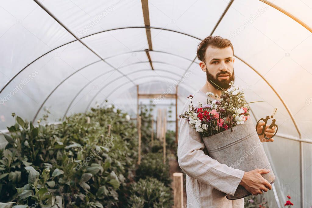 young bearded man who enjoys growing flowers, his hobby is cultivating different varieties of wildflowers at his home flower farm