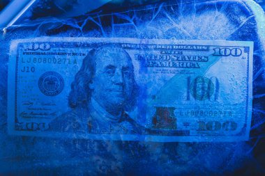 Yeni 100 dolarlık banknot buz tabakasının altında, küresel ekonomik kriz konsepti veya doların dünya piyasasına düşüşü