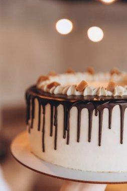 Kafe arka planında çikolata ve karamel olan iştah açıcı büyük beyaz pasta.