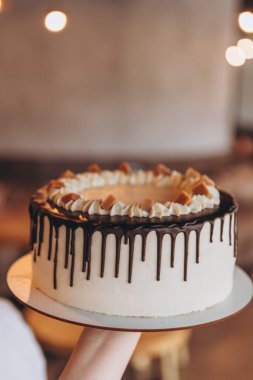 Kafe arka planında çikolata ve karamel olan iştah açıcı büyük beyaz pasta.