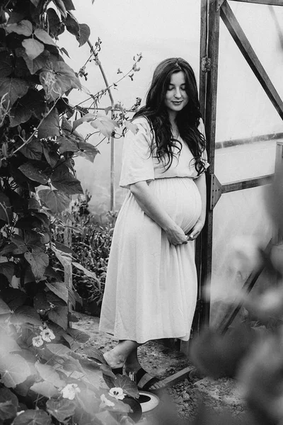 自宅のミニフラワーファームの花の間で写真のためにポーズをとって長いリネンのドレスを着たかなり若い女の子の肖像画 — ストック写真