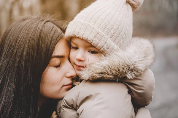 Parkta serin bir sonbahar gününde yürüyen güzel anne ve küçük kızının portresi.