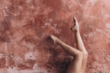 Zarif kadın bacakları. Genç bir kız bronzlaşmış güzel bacaklarını kaldırıp duvara dayayarak jimnastik yapıyor.