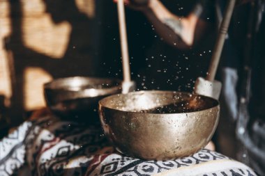 Meditasyon için Tibet bakır kasesi, bir adamın siluetinin arka planında yakın plan fotoğrafı.