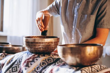 Bir adam şarkı kasesi tutuyor ve Tibet kasesi çalıyor.