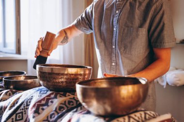 Spa salonunda Nepal Buda bakır kasesi. Genç sakallı adam masaj terapisi yapıyor. Spa 'da şarkı söylüyor. Ses terapisi, dinlenme, meditasyon, sağlıklı konsept.