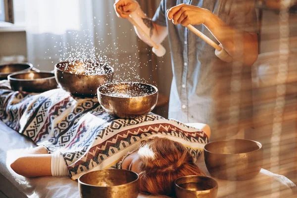 Spa salonunda Nepal Buda bakır kasesi. Genç sakallı adam masaj terapisi yapıyor. Spa 'da şarkı söylüyor. Ses terapisi, dinlenme, meditasyon, sağlıklı konsept.