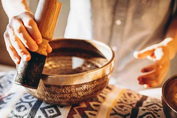 man holding and playing a singing bowl tibetan bowl