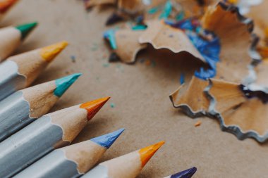 Resim atölyesi veya resim ve güzel sanatlar dersi için arka plan: Keskin renkli kalemler ve çizim kağıdındaki talaşlar