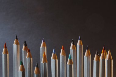 seçici odak: birbirinden farklı yüksekliklere sahip ve koyu bir arkaplan üzerinde duran birçok keskinleştirilmiş renkli kalem