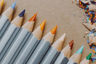 Resim atölyesi veya resim ve güzel sanatlar dersi için arka plan: Keskin renkli kalemler ve çizim kağıdındaki talaşlar