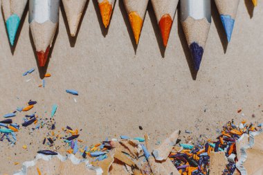 Resim atölyesi veya resim ve güzel sanatlar dersi için arka plan: Keskin renkli kalemler ve çizim kağıdındaki talaşlar