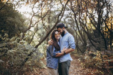 Sonbahar buğday tarlasında güneşli havanın tadını çıkararak yürüyen şık yeniyetmelerden oluşan mutlu genç bir aile. seçici odak, kopyalama alanı