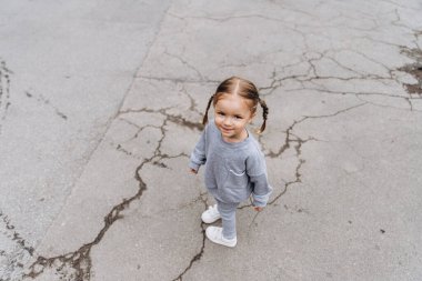 Samimi çocukların gülüşü ve eğlencesi, gülümseyen kız oynuyor ve fotoğraf için poz veriyor.